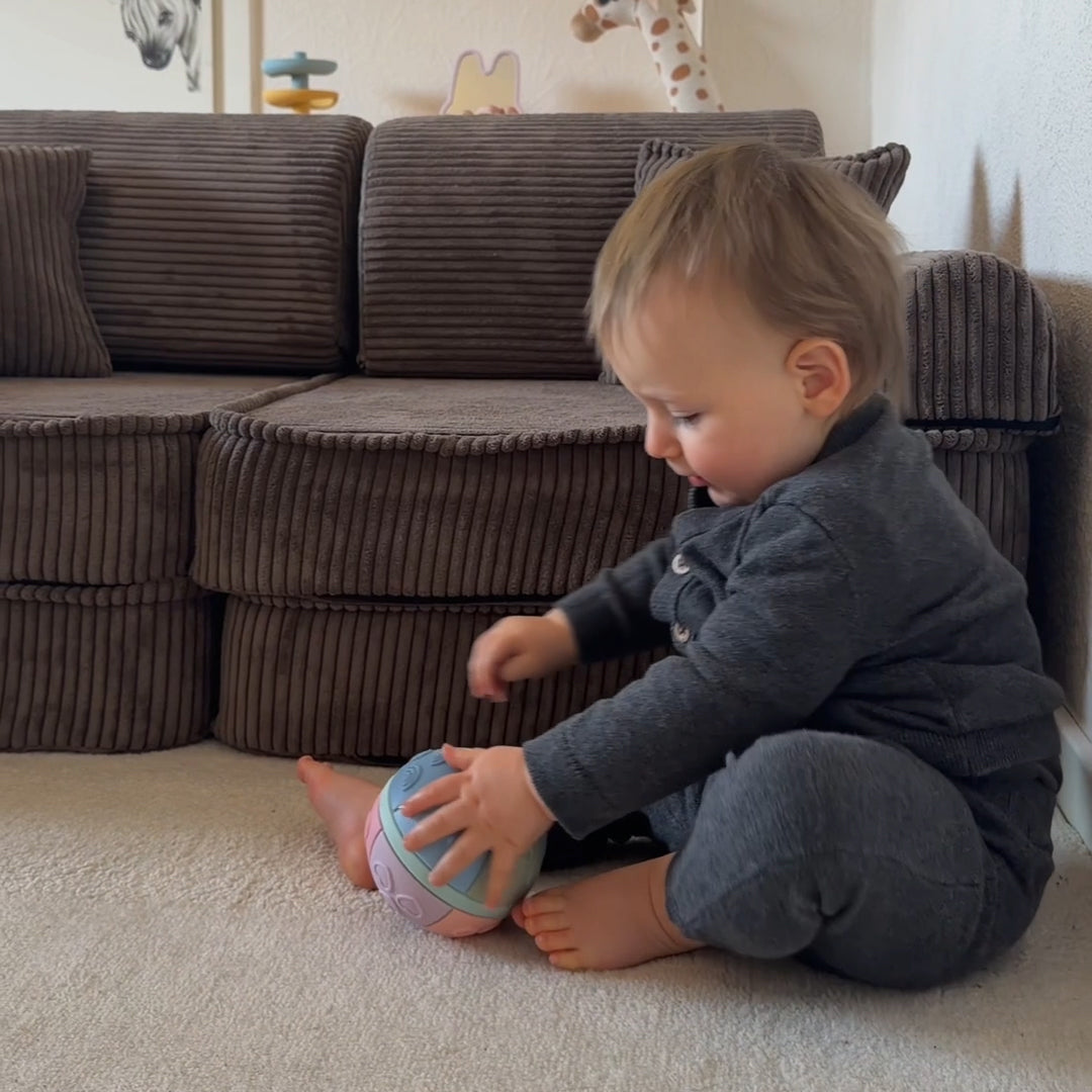 Child playing with a ball on the floor in a living room.